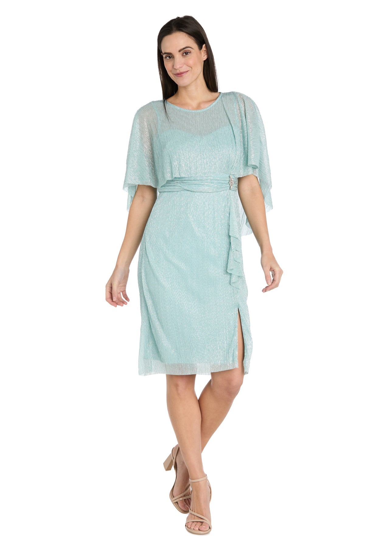 A woman stands in strappy heels against a white background, wearing the R&M Richards 3195P Caped Knee-Length Party Dress in light blue, featuring short sleeves, a belted waist, and a side slit.